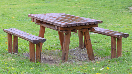 Wet Wooden Table With Benches at Grass Field Picnic Area