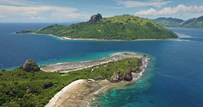 Fiji, Kuata island: Breathtaking aerial view tropical islands with lush green vegetation surrounded by crystal clear turquoise water. Mountains, white sand beach, coral reef bay. Drone flight footage