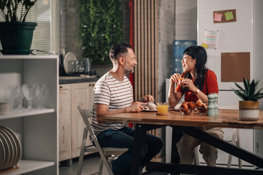 Happy couple enjoying breakfast and conversation in modern kitchen - Powered by Adobe