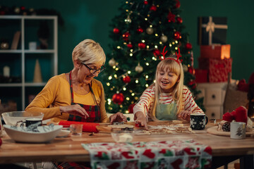 Grandmother and granddaughter making christmas cookies at home