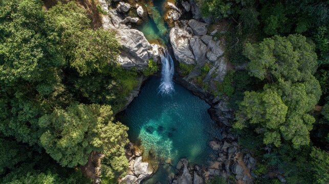 Aerial view of a beautiful waterfall cascading into a turquoise pool surrounded by lush green trees