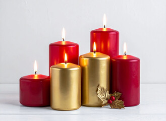 Conjunto de velas doradas y rojas encendidas, con algunas hojas de decoración, y fondo blanco.