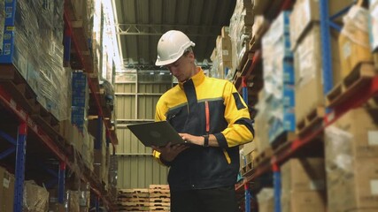 Professional male worker wearing safety helmet working industrial warehouse storing and distributing logistics goods warehouse center using laptop record and monitor goods on the shelves. - Powered by Adobe