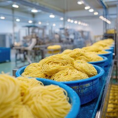 Fresh pasta in blue plastic containers on a conveyor belt in a modern food processing facility