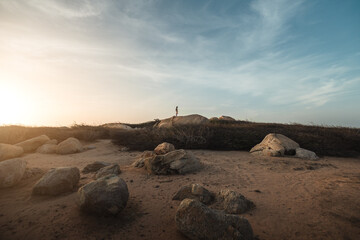 Silueta de un hombre joven latino parado sobre las rocas al atardecer/amanecer en las dunas en Aruba, hermoso atardecer en las dunas de Arashi en Aruba