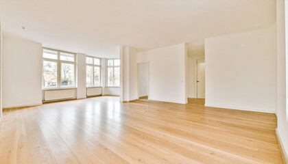 Obraz premium Spacious empty room with large windows and wooden flooring, creating bright and airy atmosphere. white walls enhance natural light, making space feel open and inviting