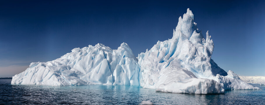 Panoramic view of the Antarctic landscape with snow-covered mountains, floating icebergs, and calm polar waters