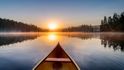 Obraz premium a tranquil sunrise over a calm lake featuring a solitary canoe reflecting in the peaceful water surrounded by misty nature