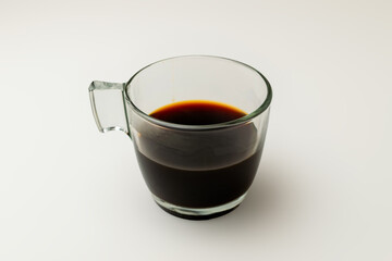 Close-up of a clear glass cup with Colombian coffee on a clean white background, ideal for coffee shops and natural product promotions.