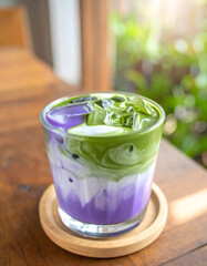 Close-up of a refreshing iced matcha and ube latte, a trendy layered drink with purple sweet potato, milk, and green tea in a glass