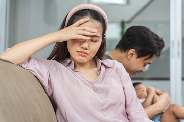 Unhappy Woman Sitting Apart from Partner and Baby on Sofa, New Mother Feeling Stressed or Unhappy,...