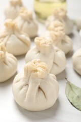 Uncooked khinkalis (dumplings) on white wooden table, closeup
