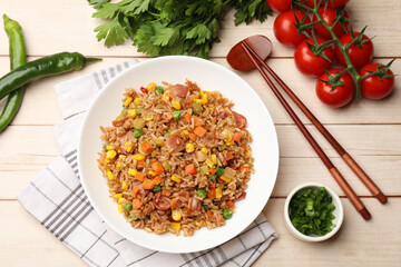 Tasty fried rice, products and chopsticks on light wooden table, flat lay
