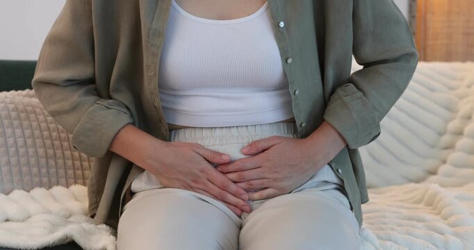 Woman suffering from cystitis symptoms on sofa at home, closeup