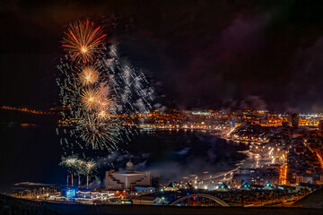Colorful fireworks exploding over las palmas de gran canaria city by the atlantic ocean at night