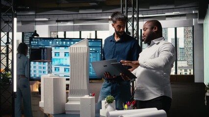 Multiethnic group of developers and contractors discussing urban housing models and blueprints layout revisions for upcoming residential development project. Smart city planning session. Camera A. - Powered by Adobe