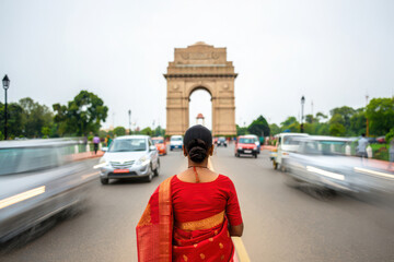 Woman in red saree walks towards india gate monument in delhi