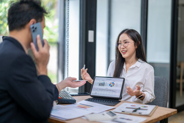 Businesswoman showing charts on tablet to businessman talking on phone