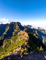 Mountain peak trail, vibrant green slopes, hazy clouds