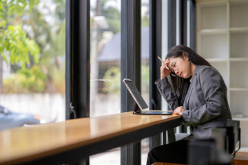Stressed businesswoman having headache while working on laptop in cafe