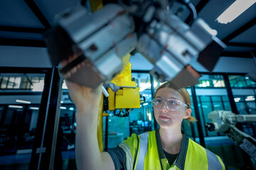A female automation engineer oversees the operation of a 6-axis industrial robotic arm in a smart factory, representing human oversight in a complex Industry 4.0 environment.