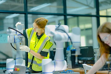 Two female students in a technology class work with robotic arms. They are learning about programming and automation, preparing for careers in engineering and advanced manufacturing.