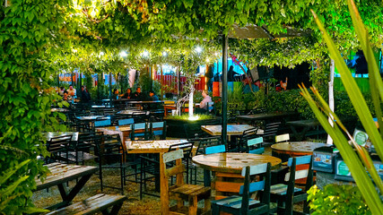 Restaurante al aire libre con mesas de madera en terraza verde