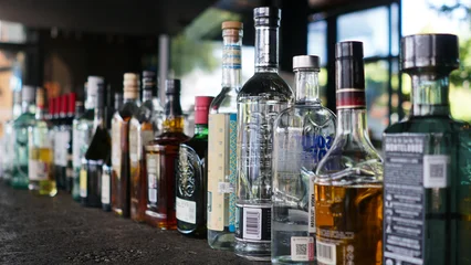Selbstklebende Fototapeten Bar Botellas de licor alineadas en barra de bar  © rafael