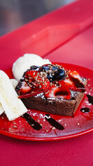 Brownie con helado y plátano servido en plato rojo