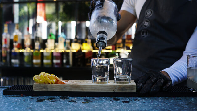 Bartender sirviendo vodka en vasos de shot