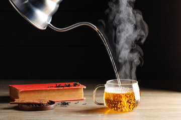 Hot tea is poured into glasses with steam. Teacups are placed on the table in the warm atmosphere of morning sunlight.
