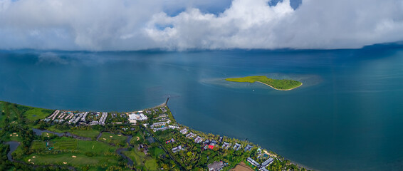 Expansive aerial view of a luxurious tropical resort and golf course on the coast, with a small,...
