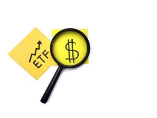 The word ETF is written on colorful note paper, viewed through a magnifying glass isolated on white background. Financial or investment concepts. Copy space 