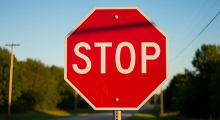 Obraz premium stop sign on a road, Red stop traffic sign with bold white letters, symbolizing caution and road safety. Ideal for transportation, urban scenes, signage concepts, and driving-related themes in high