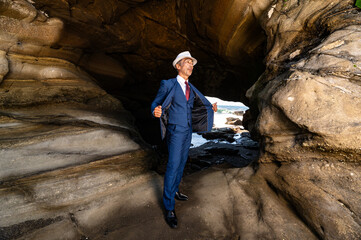 海の洞窟に立つスーツ姿の紳士　挑戦と決断を象徴するビジネスイメージ