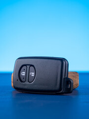Close up of black car key with open and close buttons on blue background