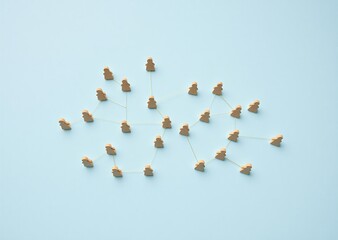 Small wooden figures interconnected on a light blue surface, representing a complex network of social or business connections.