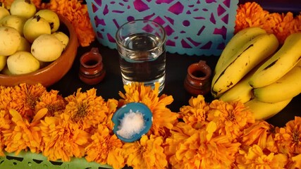 Traditional Day of the Dead altar arrangement with decorative elements such as cempasuchil flowers, candles, papel picado, and food