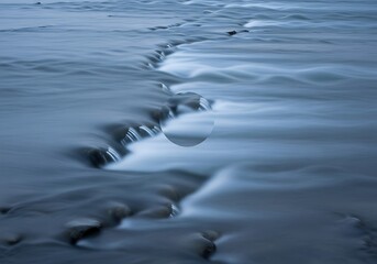 Obraz premium Serene river flowing over rocks with mystical transparent sphere