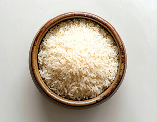 White rice grain in brown ceramic bowl top view on white surface natural light