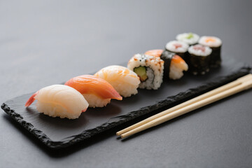 Assorted Sushi Rolls on Black Slate Plate with Chopsticks