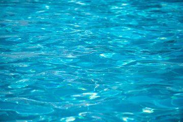 Water background. Blue water, ripples and highlights. Texture of water surface and tiled bottom.