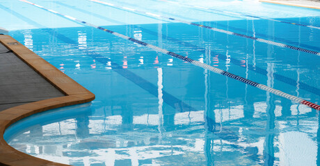 Clear blue swimming pool with floating lane markers, prepared for swim practice or competition in a controlled indoor environment