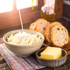 Creamy ricotta in a bowl with slices of bread and butter. Sunlight streams in