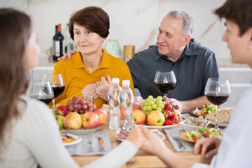 Father and mother together with adult children talking at the dinner table at home