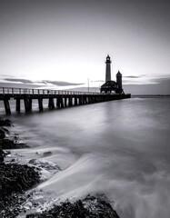Black and white seascape with lighthouse on pier