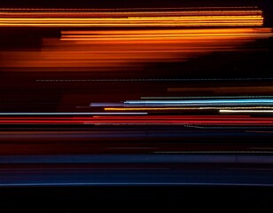 Abstract long exposure photograph of colorful light trails from city traffic streaking across a dark background.