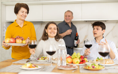Father and mother together with adult children talking at the dinner table at home