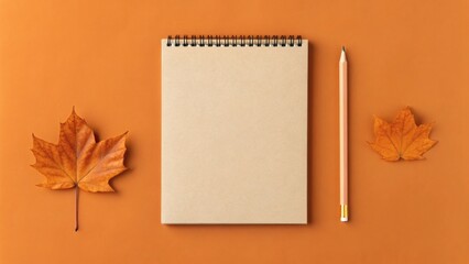 Notebook with Pencil and Autumn Leaves on Orange Background