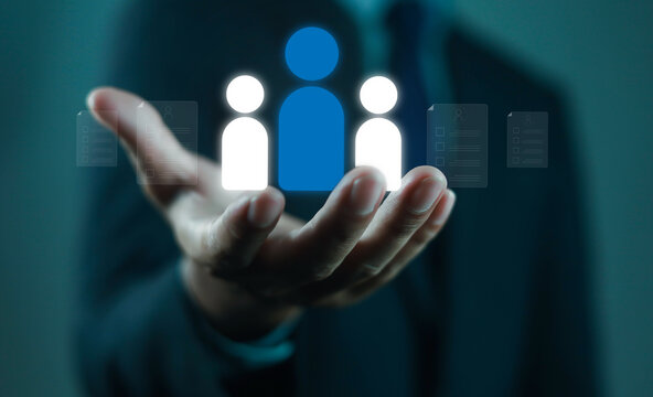 Businessman holding digital human resource icon with employee profiles, symbolizing recruitment, HR management, staff selection, corporate workforce strategy, and human capital development in modern.